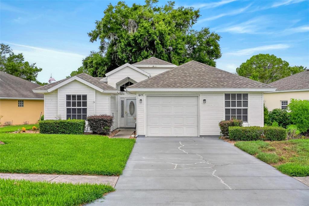 A single-story house with white siding, a gray shingled roof, and a concrete driveway — 615 JUNIPER WAY, TAVARES, FL