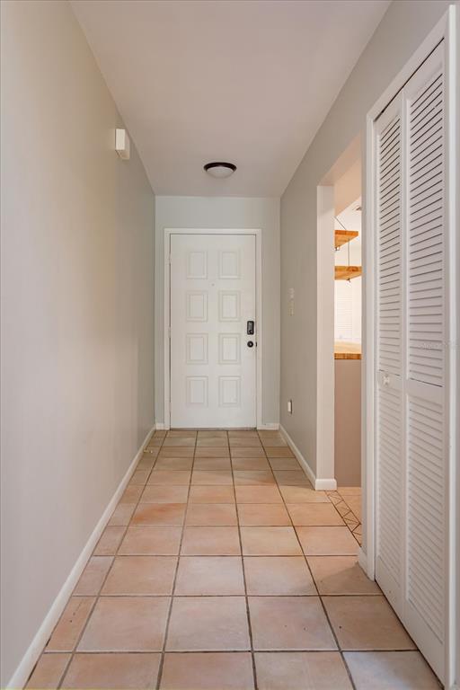 A tiled entryway leads to a white front door with a louvered closet door nearby — 5429 VINELAND ROAD UNIT 6F, ORLANDO, FL