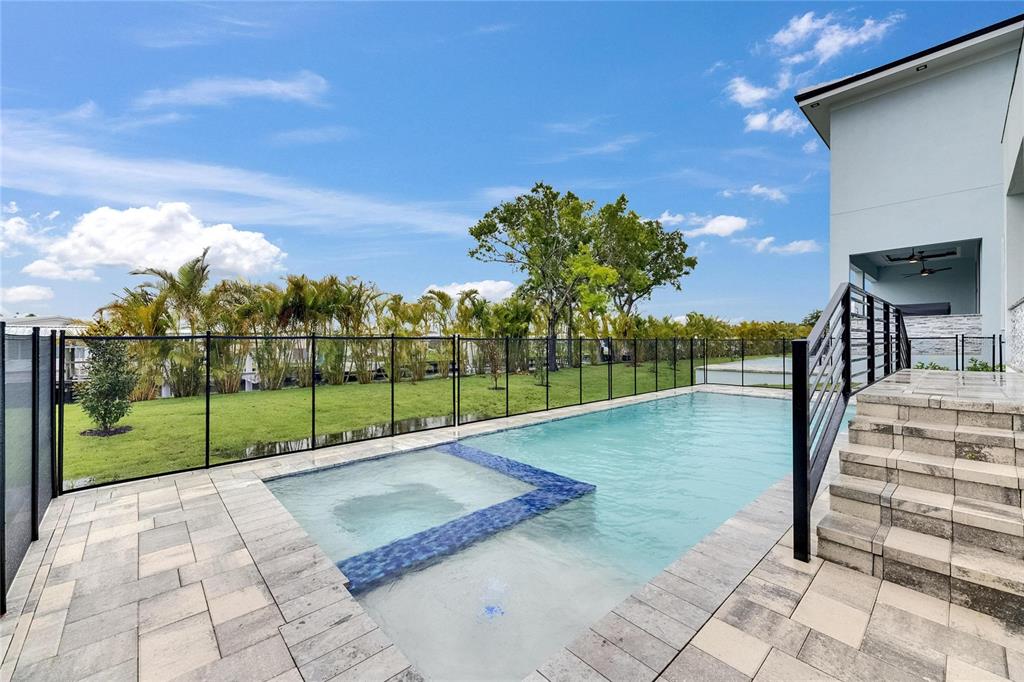 An outdoor swimming pool with an integrated spa sits on a paved patio beside a house — 6528 SIMONE SHORES CIRCLE, APOLLO BEACH, FL
