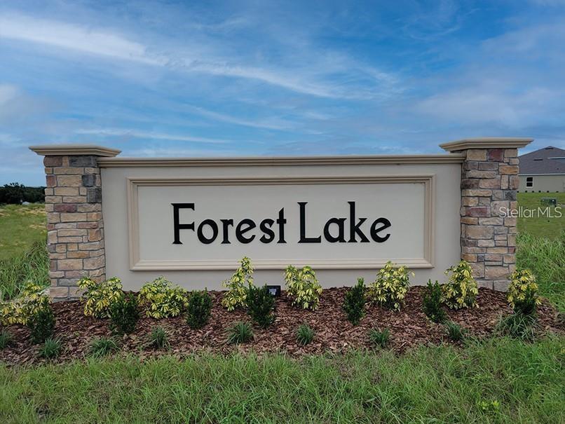 A stone and stucco monument sign for Forest Lake stands in a grassy field — 1847 BUCKEYE ROAD, DAVENPORT, FL