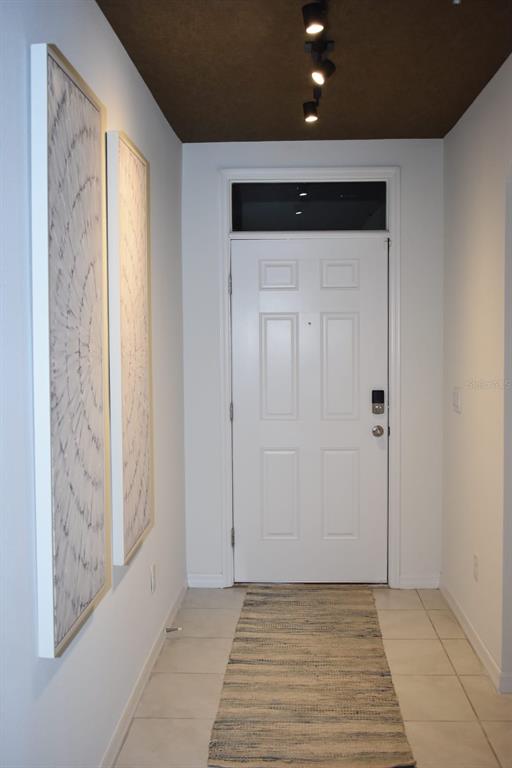 A hallway features a white door, light tile flooring, two wall art pieces, and a dark ceiling — 1847 BUCKEYE ROAD, DAVENPORT, FL