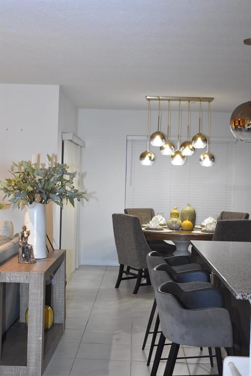 A dining area with a round table, upholstered chairs, and a modern multi-light pendant fixture — 1847 BUCKEYE ROAD, DAVENPORT, FL
