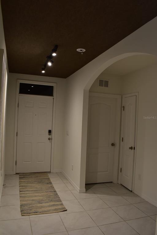 An entryway with white tile floors, a dark brown ceiling, and an arched doorway — 1847 BUCKEYE ROAD, DAVENPORT, FL
