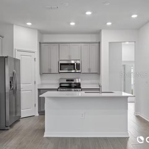 A modern kitchen features gray cabinets, stainless steel appliances, and a white kitchen island — 4123 CONJUNCTION WAY, APOPKA, FL