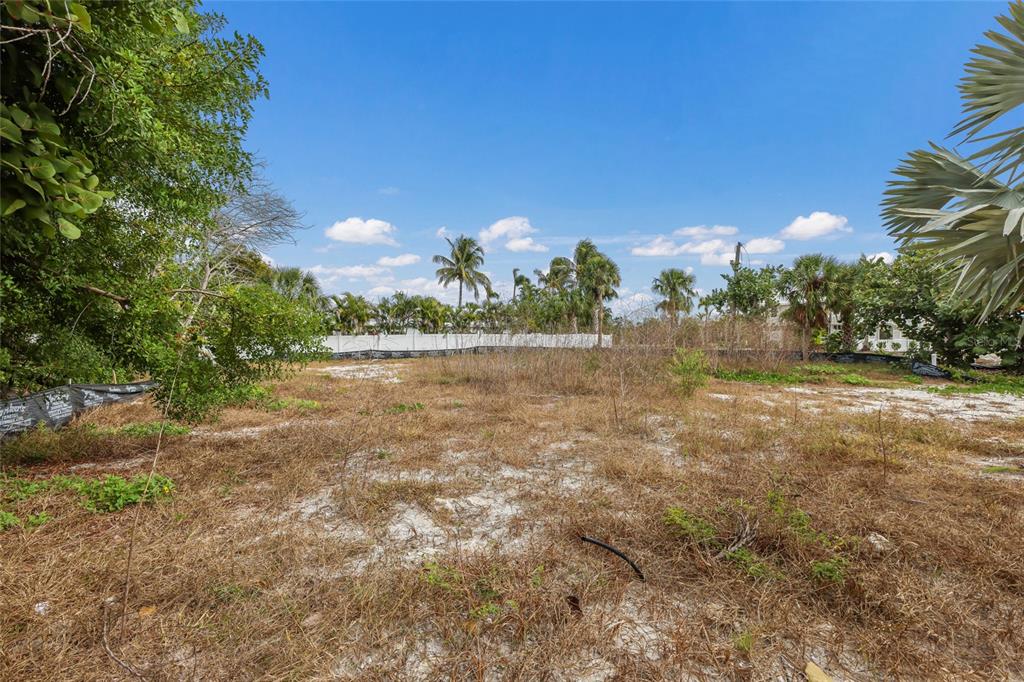 A vacant, sandy lot features patches of dry grass, scattered trees, and a white fence — 6500 GULFSIDE ROAD, LONGBOAT KEY, FL