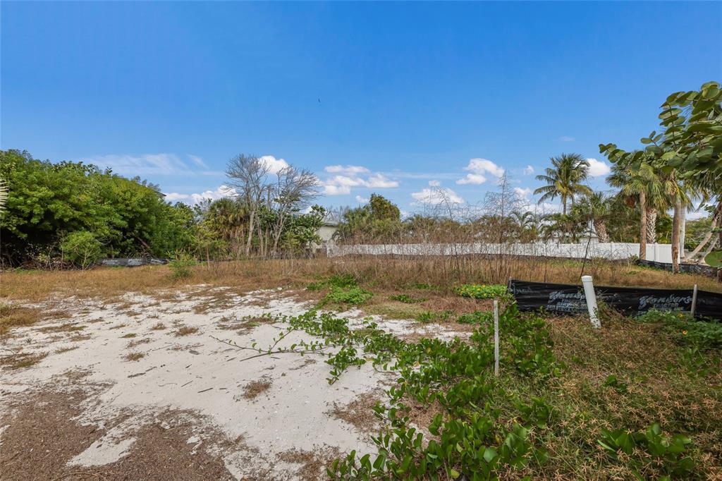 A vacant, sandy lot features sparse vegetation and a black silt fence under a blue sky — 6500 GULFSIDE ROAD, LONGBOAT KEY, FL