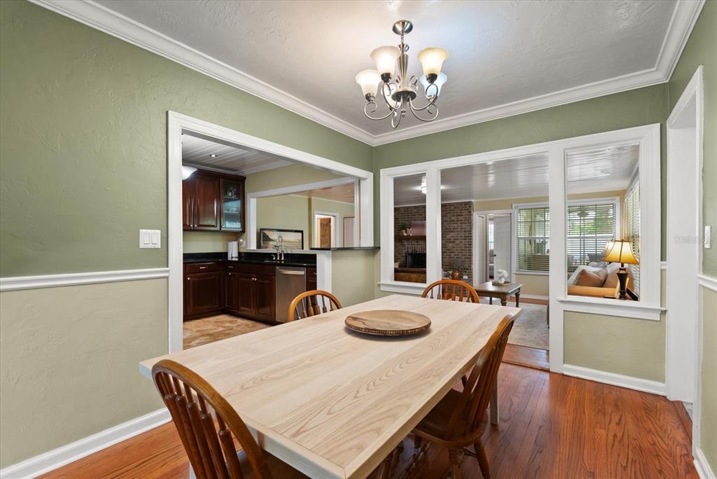A dining room features a light wood table, green walls, and views into the kitchen — 37 E VANDERBILT STREET, ORLANDO, FL