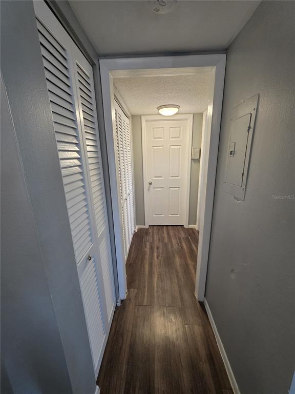 A hallway with wood-look flooring, white louvered closet doors, and a white interior door — 705 1ST STREET UNIT 4, INDIAN ROCKS BEACH, FL