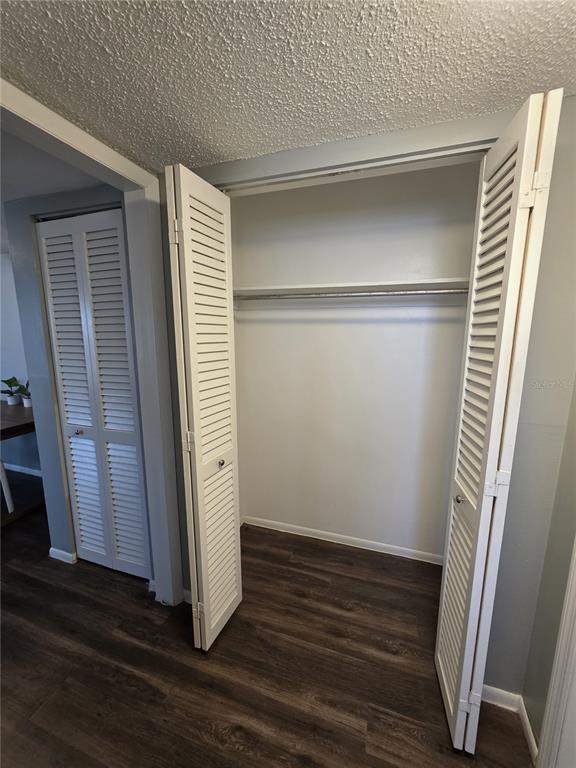 An open closet with louvered doors, a shelf, and a hanging rod over wood-look flooring — 705 1ST STREET UNIT 4, INDIAN ROCKS BEACH, FL