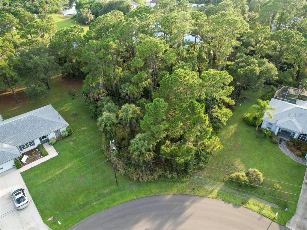 An aerial view shows a vacant, wooded lot situated between two residential houses on a cul-de-sac — Lot 19 ALBREN STREET, NORTH PORT, FL