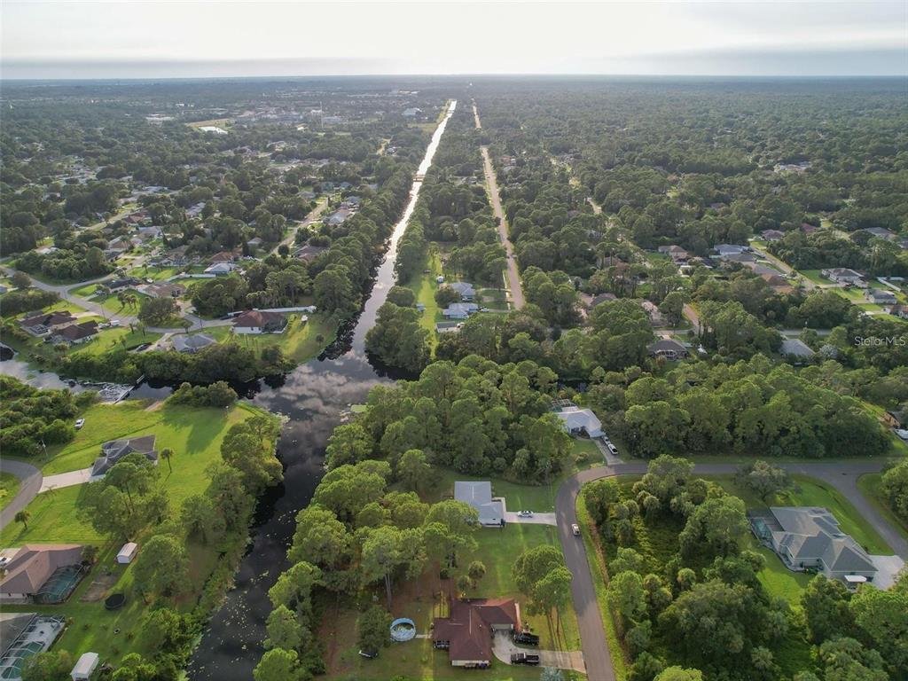 An aerial view shows a residential neighborhood with a canal running through wooded lots — Lot 19 ALBREN STREET, NORTH PORT, FL