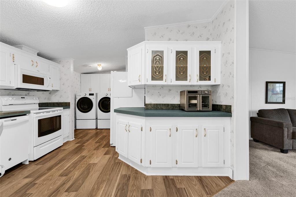 A kitchen with white cabinets, green countertops, and a laundry area with a washer and dryer — 1000 KINGS HIGHWAY UNIT 380, PORT CHARLOTTE, FL
