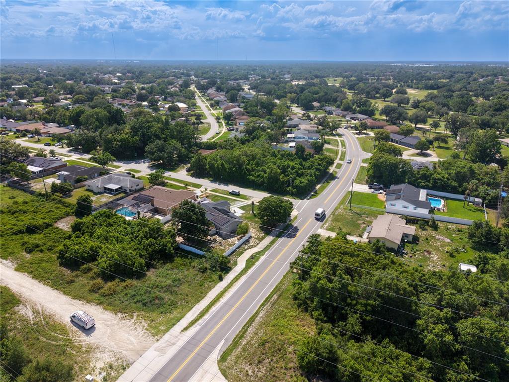 An aerial view shows a suburban neighborhood with houses, swimming pools, and a paved road — 2067 E BARLINGTON DRIVE, DELTONA, FL