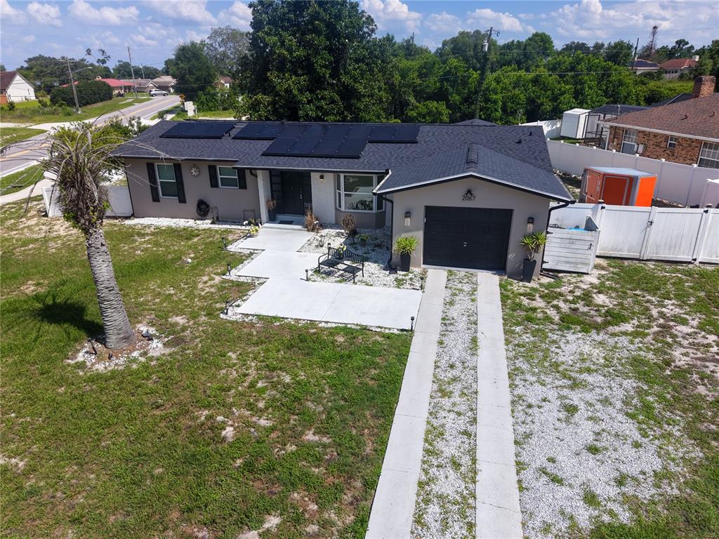An aerial view shows a single-story house with a dark roof, solar panels, and driveway — 2067 E BARLINGTON DRIVE, DELTONA, FL