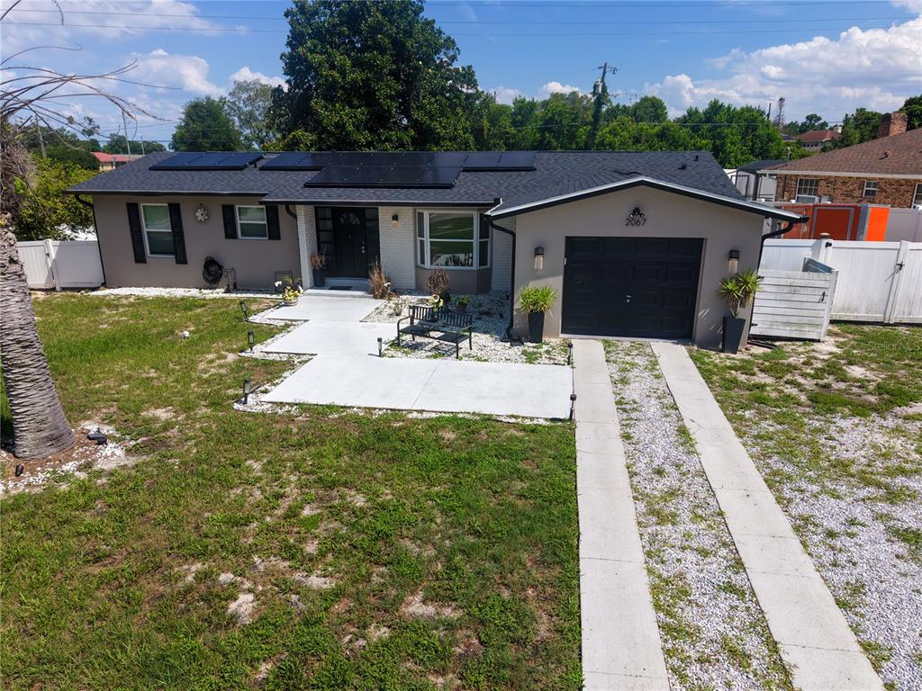 An aerial view of a single-story house with a solar panel roof and gravel driveway — 2067 E BARLINGTON DRIVE, DELTONA, FL