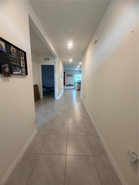 A tiled hallway leads from the foreground toward an open-concept kitchen and living area — 297 MEADOWBROOK BOULEVARD, WINTER HAVEN, FL
