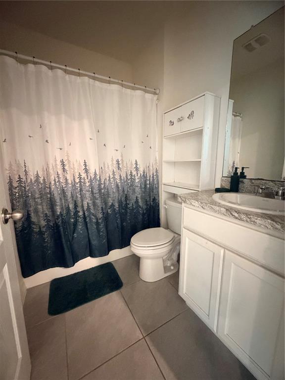 A bathroom features a forest-print shower curtain, a white toilet, and a vanity with storage — 297 MEADOWBROOK BOULEVARD, WINTER HAVEN, FL