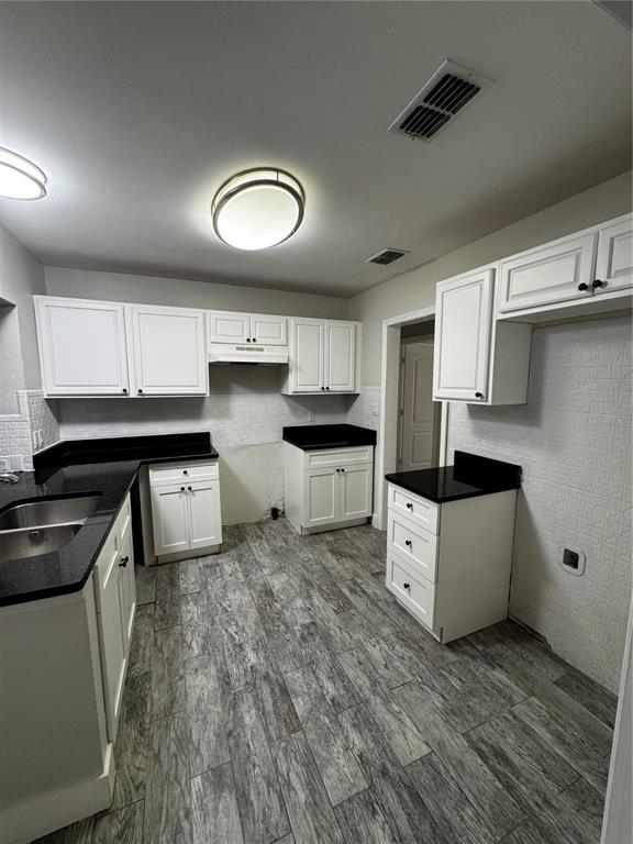 A kitchen features white cabinets, black countertops, and gray wood-look tile flooring — 2552 COLUMBUS STREET, FORT MYERS, FL