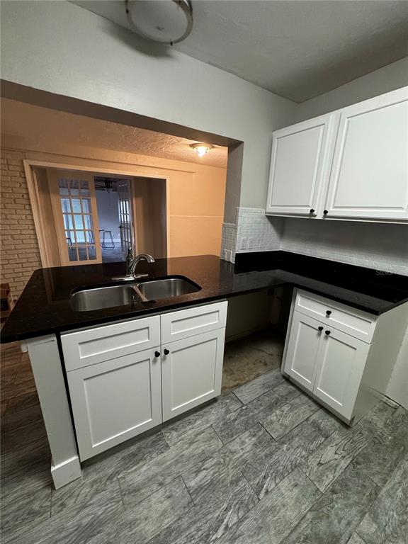 A kitchen features white cabinets, a black countertop with a sink, and gray wood-look flooring — 2552 COLUMBUS STREET, FORT MYERS, FL