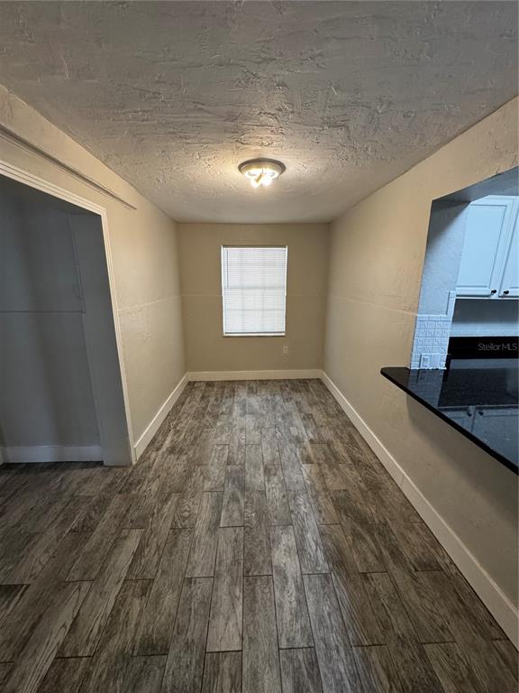 A dining area with wood-look tile flooring, a single window, and a kitchen pass-through — 2552 COLUMBUS STREET, FORT MYERS, FL