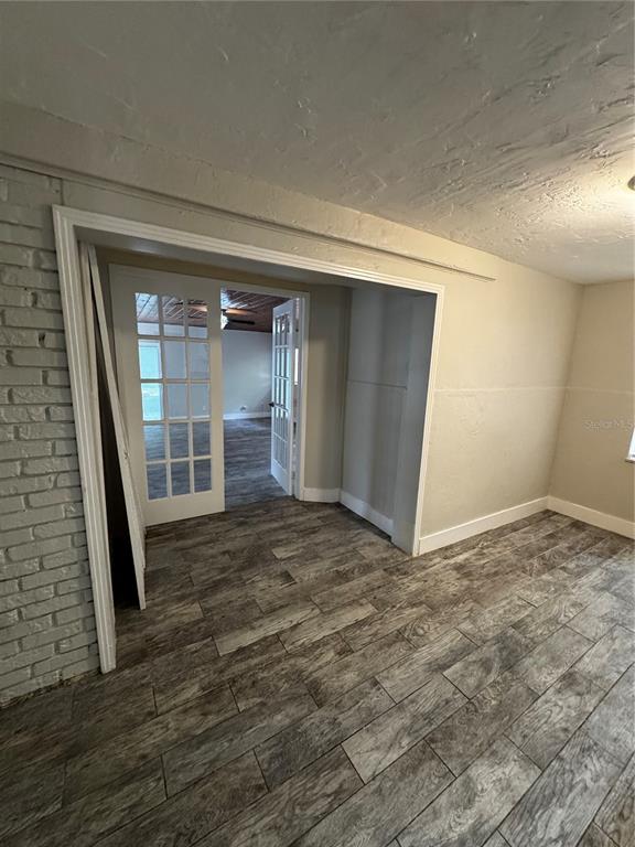 A room with wood-look tile flooring and a white brick wall leads through French doors — 2552 COLUMBUS STREET, FORT MYERS, FL