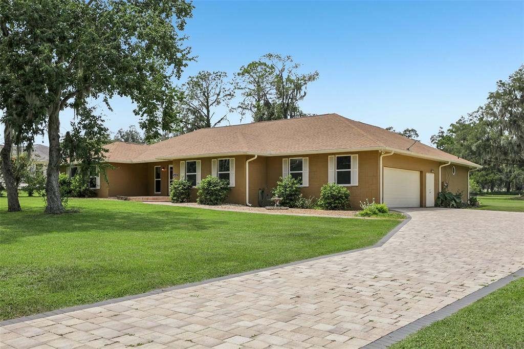 A single-story house with a tan exterior, brown roof, and a paved driveway — 4410 NW 76TH COURT, OCALA, FL