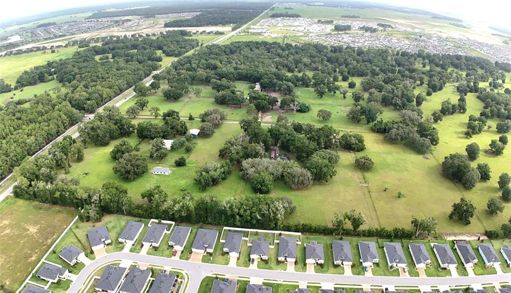 An aerial view shows a large grassy lot with scattered trees bordering a suburban neighborhood — 7119 SW 80TH AVENUE, OCALA, FL