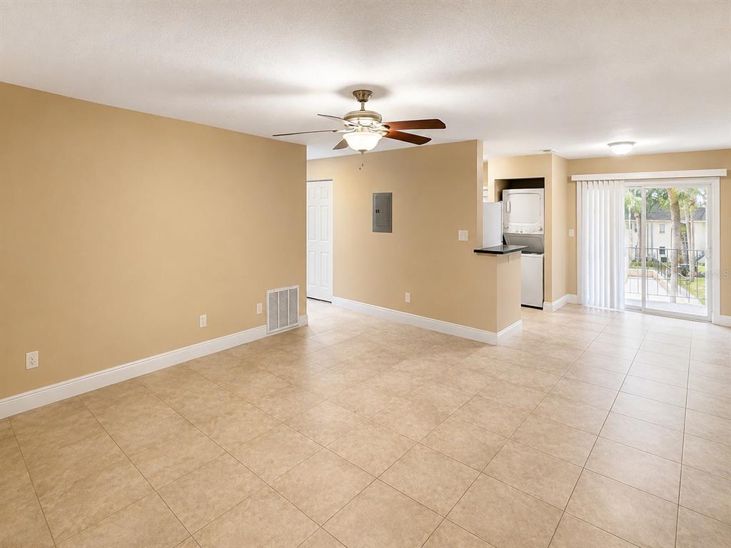 An open living area with tan walls, tile flooring, a ceiling fan, and a laundry closet — 2800 E 113TH AVENUE UNIT 213, TAMPA, FL