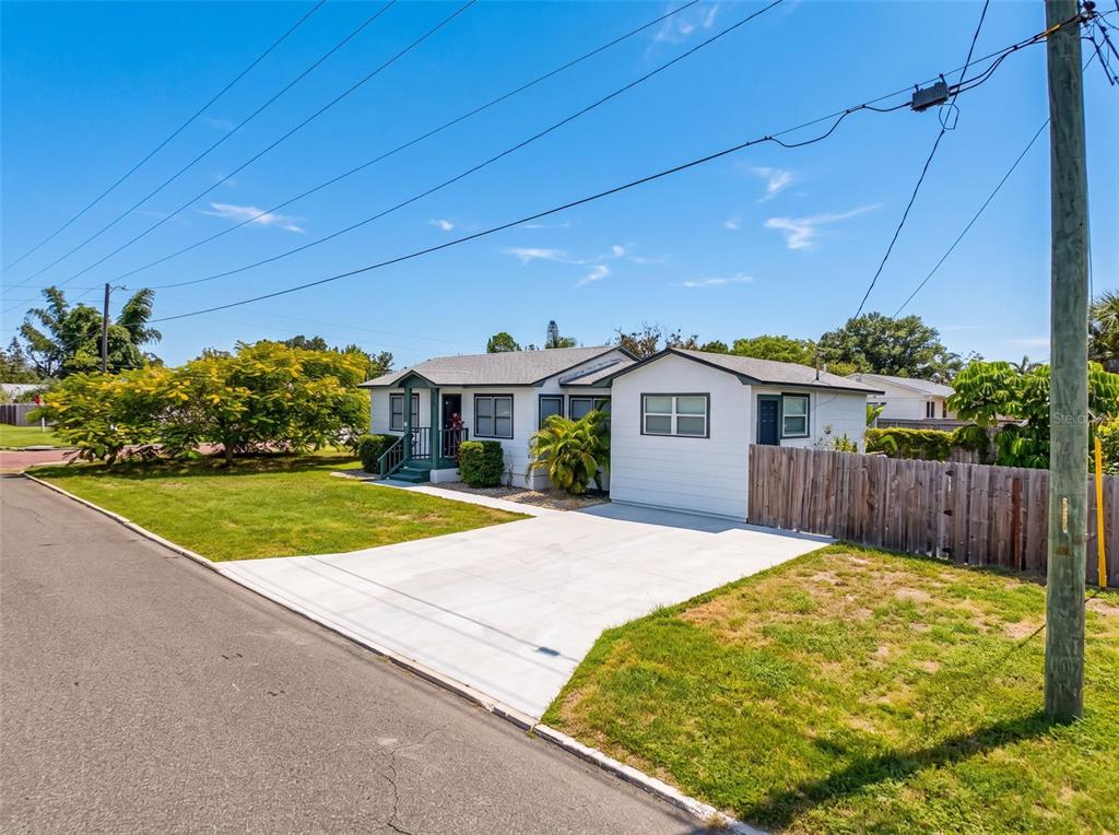 A single-story white house with a concrete driveway, green trim, and a wooden fence — 440 42ND STREET N, ST PETERSBURG, FL