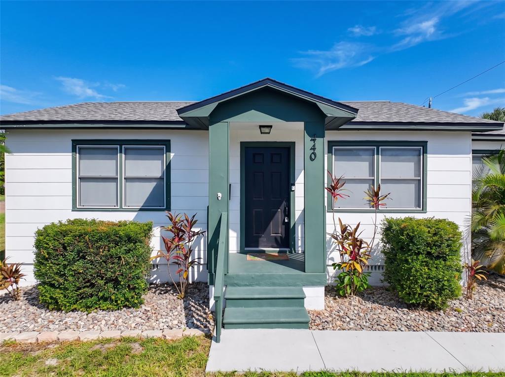 A white house with a dark green door and trim features a small front porch — 440 42ND STREET N, ST PETERSBURG, FL
