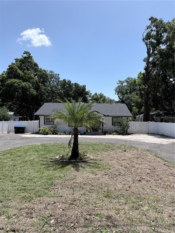 A single-story house with a white exterior and dark roof sits behind a palm tree — 1243 DINGENS AVENUE, WINDERMERE, FL