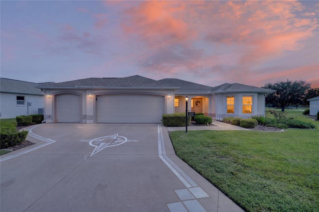 A single-story house with a three-car garage and a concrete driveway at sunset — 3147 MANSFIELD STREET, THE VILLAGES, FL