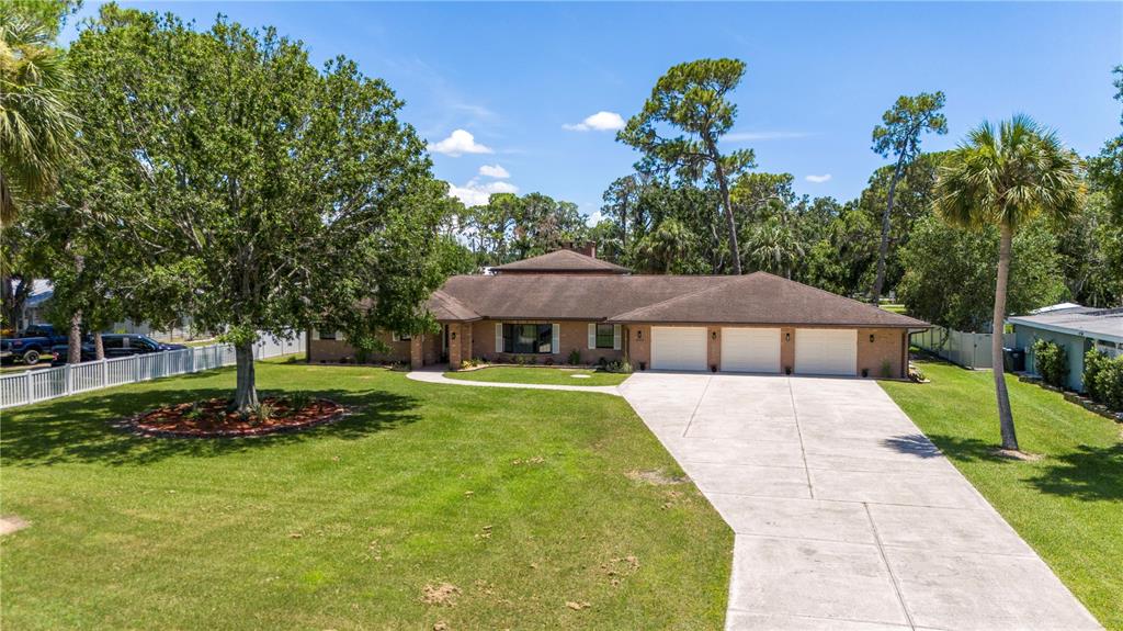 A single-story brick house with a three-car garage and a large front lawn — 404 DICKMAN DRIVE SW, RUSKIN, FL