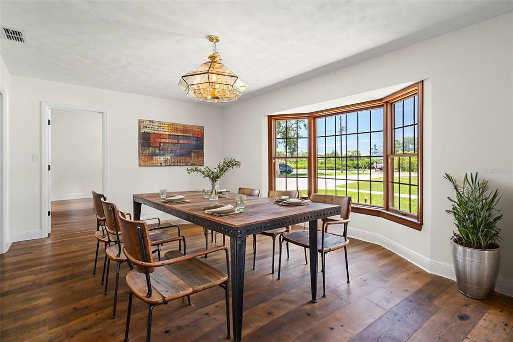 A dining room features a wooden table, metal chairs, a bay window, and hardwood floors — 404 DICKMAN DRIVE SW, RUSKIN, FL