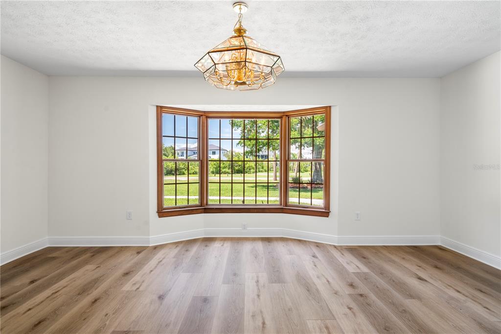 An empty dining room features light wood flooring, white walls, and a large bay window — 404 DICKMAN DRIVE SW, RUSKIN, FL
