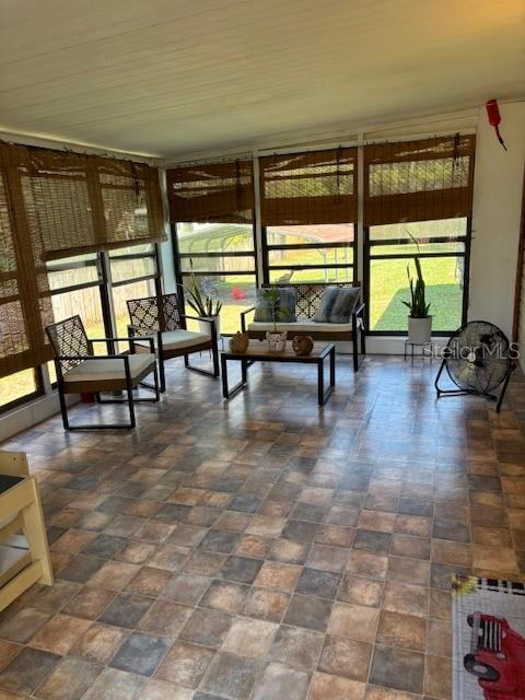 A sunroom features tiled flooring, bamboo shades, and a seating area with chairs and a bench — 1749 ELIZABETH STREET, NEW SMYRNA BEACH, FL