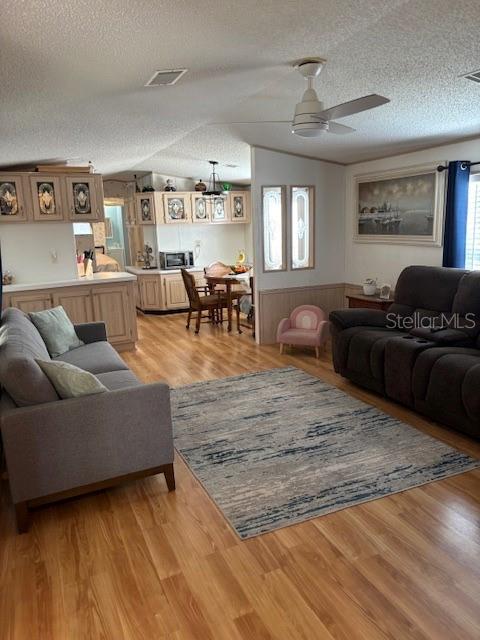 A living room with wood-look flooring, a grey sofa, a dark recliner, and a ceiling fan — 1749 ELIZABETH STREET, NEW SMYRNA BEACH, FL