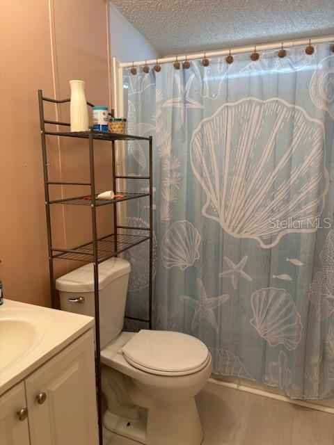 A bathroom features a toilet with an over-the-toilet storage rack and a seashell-patterned shower curtain — 1749 ELIZABETH STREET, NEW SMYRNA BEACH, FL