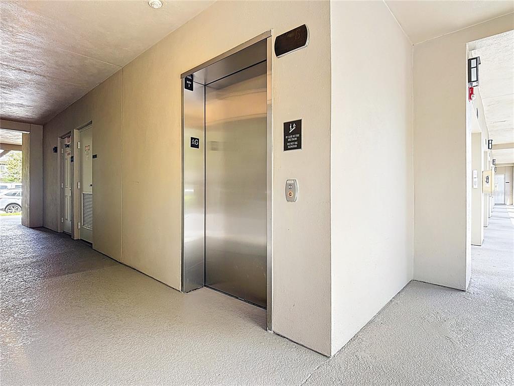 A stainless steel elevator door is set into a beige wall in an outdoor hallway — 1231 WRIGHT CIR UNIT 308, CELEBRATION, FL