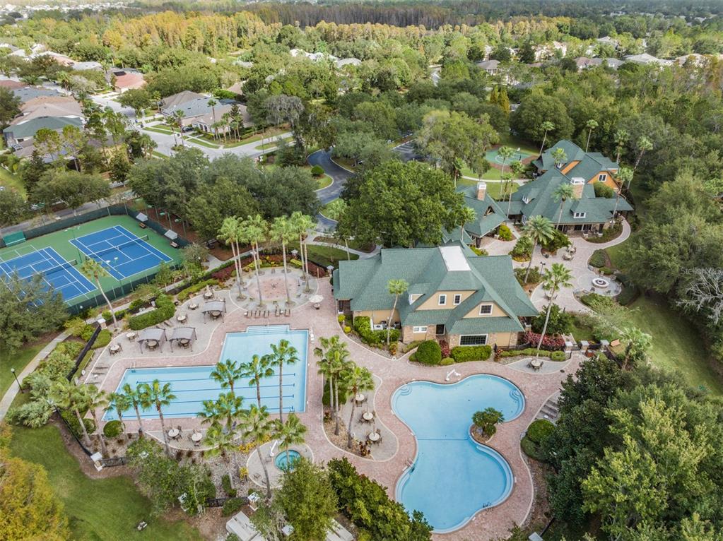 An aerial view shows houses with screened pools near a lake and community swimming pools — 21246 QUIET HAVEN COURT, LAND O LAKES, FL