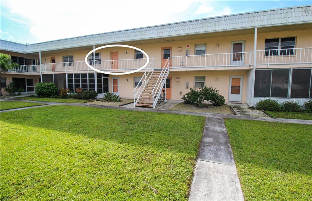 A two-story apartment building exterior features a white metal balcony and an outdoor staircase — 460 BASE AVENUE E UNIT 125, VENICE, FL