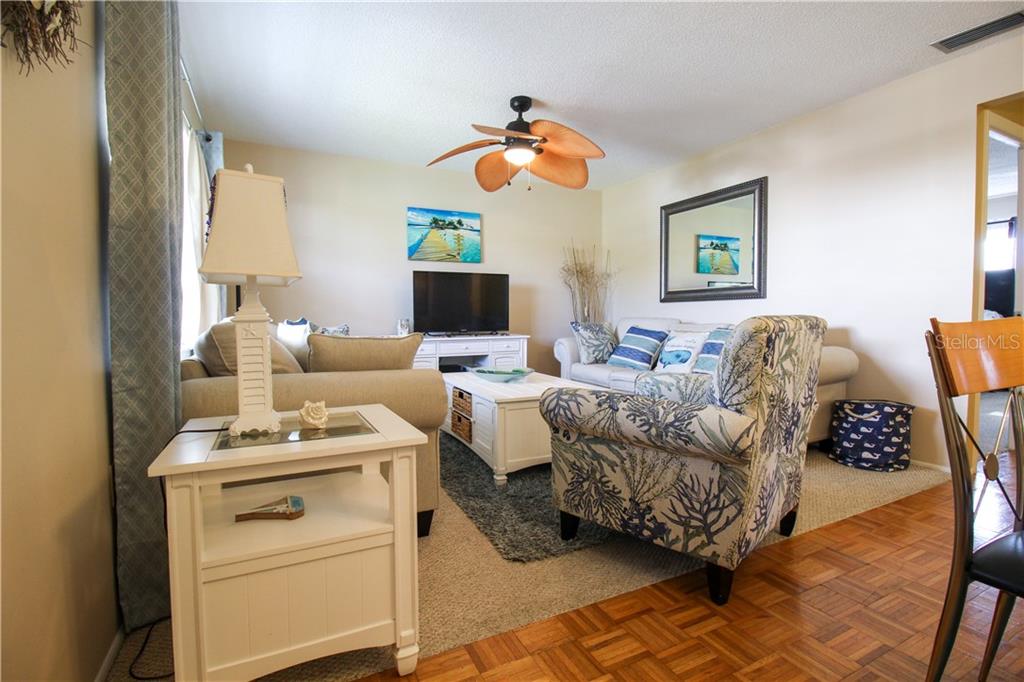 A living room features a ceiling fan, a white coffee table, and coastal-themed furniture — 460 BASE AVENUE E UNIT 125, VENICE, FL