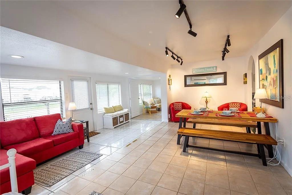 A living and dining area with tile floors, a red sofa, and a wooden dining set — 839 3RD STREET N, SAFETY HARBOR, FL