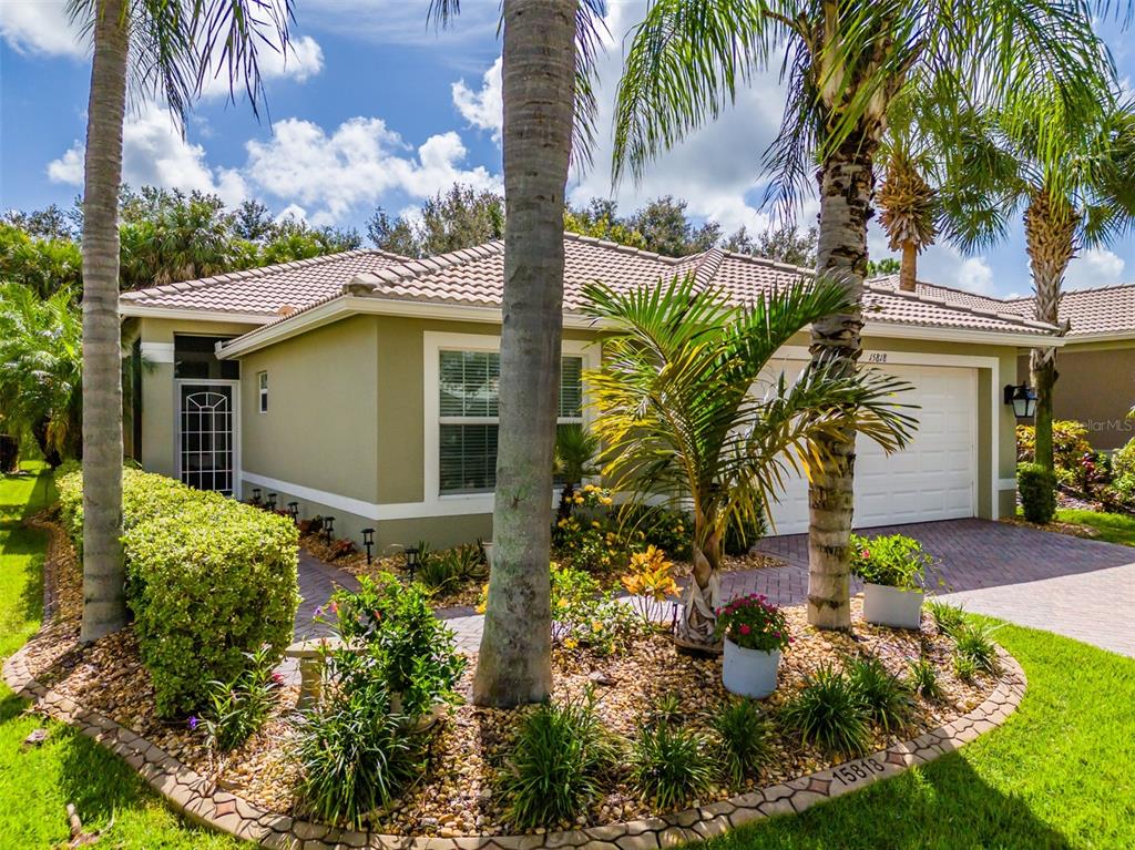 A single-story house with a tan exterior, tiled roof, and a landscaped front yard — 15818 COBBLE MILL DRIVE, WIMAUMA, FL