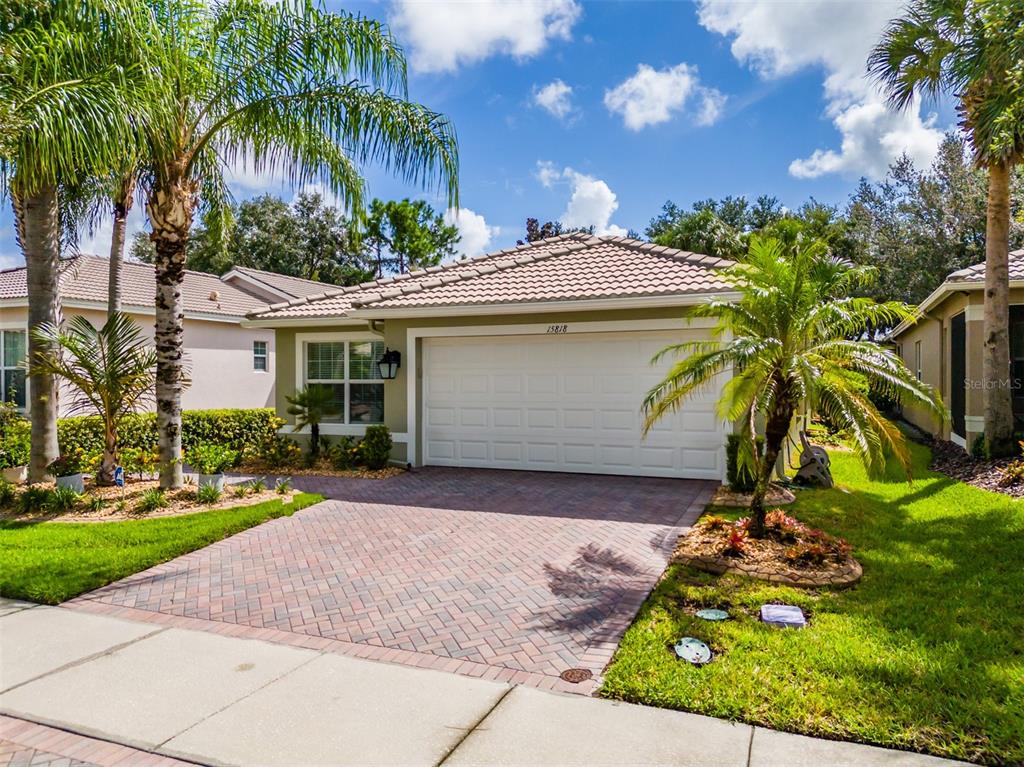 A single-story house with a paved driveway, a two-car garage, and palm trees in front — 15818 COBBLE MILL DRIVE, WIMAUMA, FL