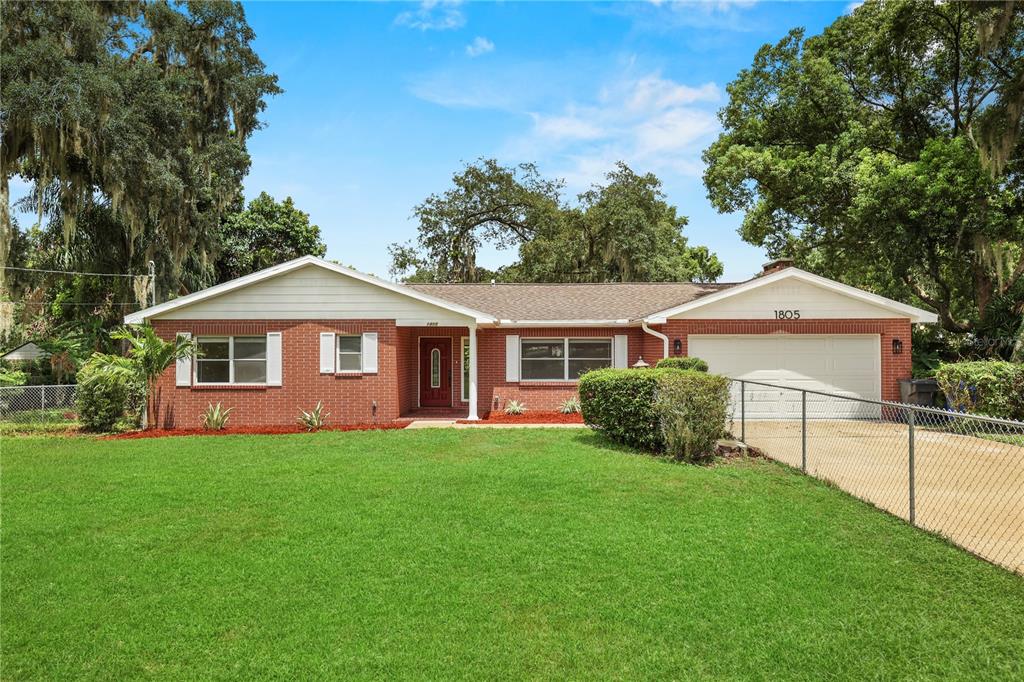 A single-story brick house with a white garage and a large front lawn — 1805 DIERKER DRIVE, VALRICO, FL