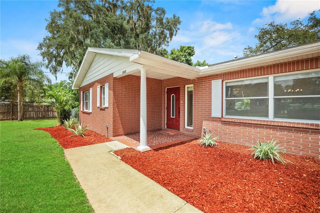 A red brick house features a covered front porch with a white column and red door — 1805 DIERKER DRIVE, VALRICO, FL