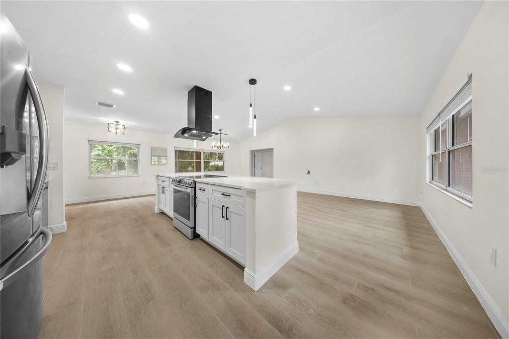 A bright kitchen features white cabinets, a central island with a range, and wood-look flooring — 1805 DIERKER DRIVE, VALRICO, FL