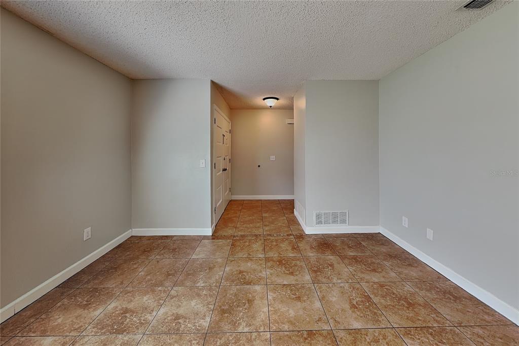 An empty room with light gray walls, a textured ceiling, and brown tiled flooring — 1016 MANCHESTER CIRCLE, WINTER PARK, FL
