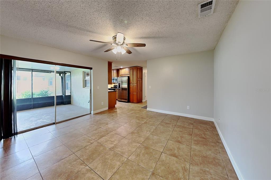 A tiled dining area with a ceiling fan opens to a kitchen and screened patio — 1016 MANCHESTER CIRCLE, WINTER PARK, FL